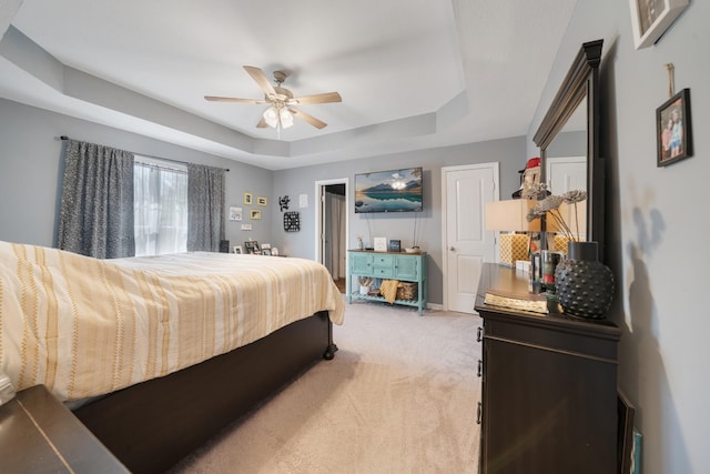 bedroom with baseboards, a tray ceiling, a ceiling fan, and light colored carpet