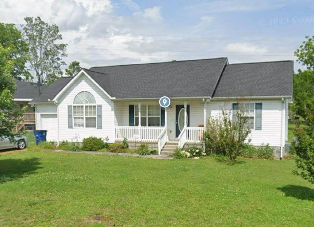 ranch-style home with a garage, covered porch, and a front yard