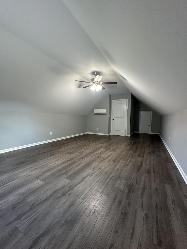 bonus room featuring a wall unit AC, vaulted ceiling, baseboards, and dark wood finished floors