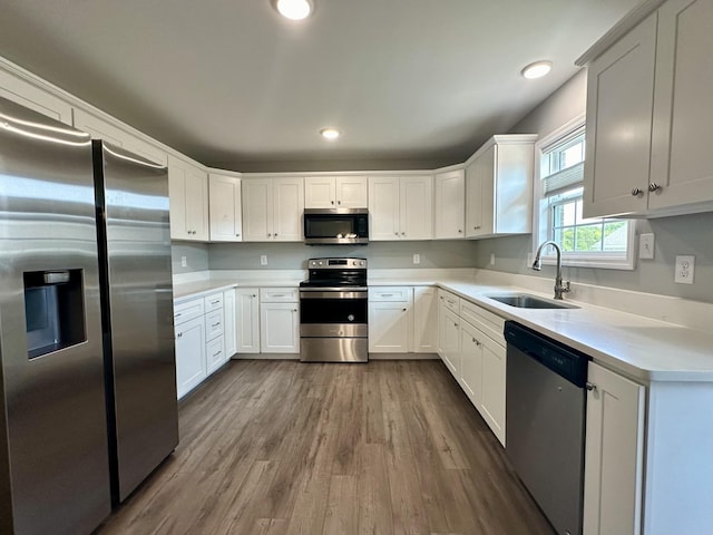 kitchen with appliances with stainless steel finishes, dark wood-style flooring, a sink, and light countertops