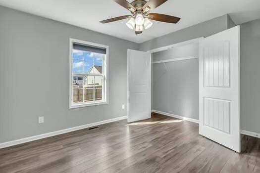 unfurnished bedroom with ceiling fan, a closet, wood finished floors, and baseboards