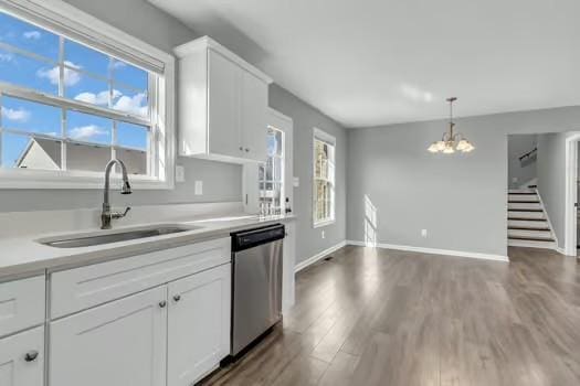 kitchen with wood finished floors, light countertops, stainless steel dishwasher, white cabinetry, and a sink