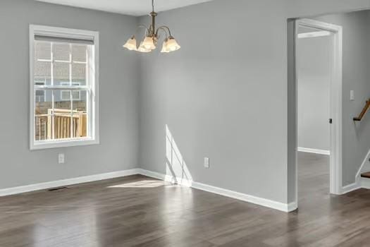 unfurnished dining area with dark wood finished floors, stairway, baseboards, and an inviting chandelier