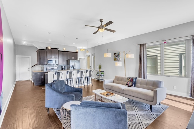 living room with baseboards, a ceiling fan, dark wood-type flooring, and recessed lighting