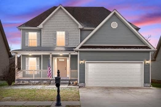 traditional-style house with a garage, concrete driveway, and a porch