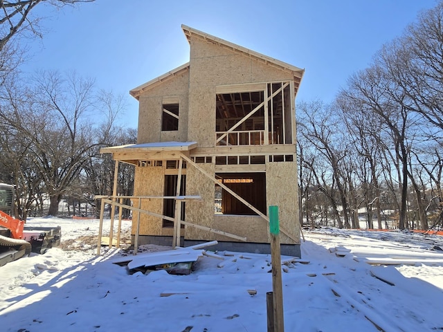 snow covered rear of property featuring stucco siding