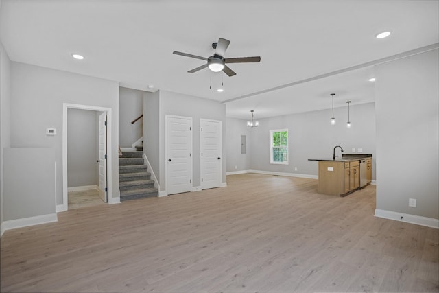 348 Welchwood Dr, Clarksville, TN 37040 - unfurnished living room featuring a sink, light wood-style floors, stairs, baseboards, and ceiling fan with notable chandelier
