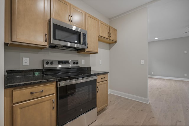 348 Welchwood Dr, Clarksville, TN 37040 - kitchen with dark stone countertops, appliances with stainless steel finishes, light wood-style floors, light brown cabinets, and baseboards