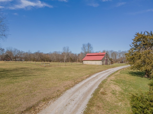 view of street featuring a rural view, dirt driveway, and a barn