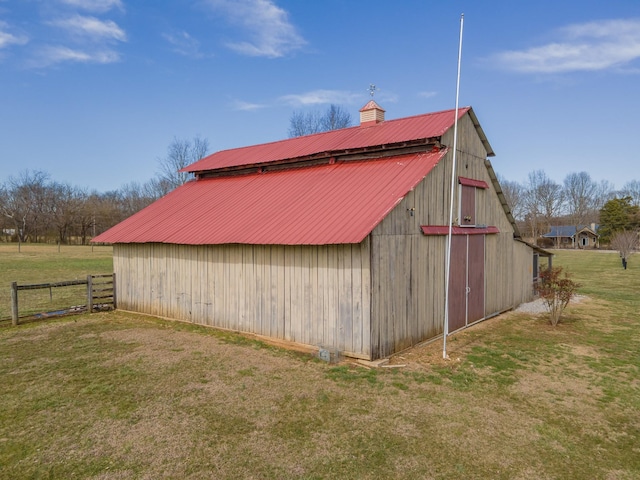 view of barn with a lawn and fence