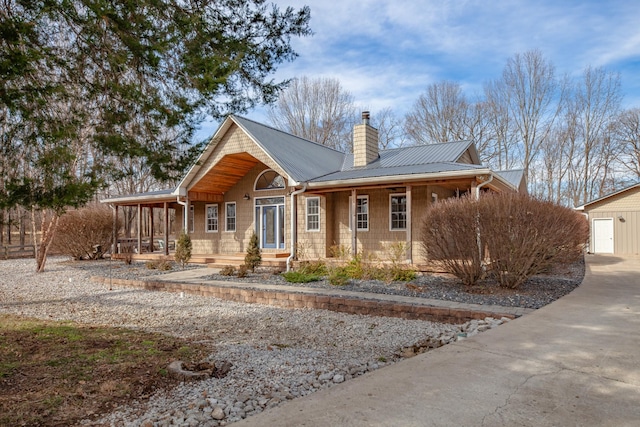 view of front of property with covered porch, a chimney, and metal roof