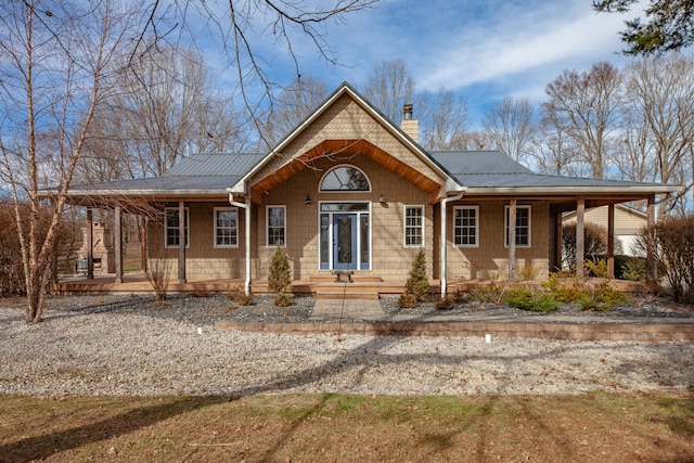 rear view of property with metal roof, a porch, and a chimney