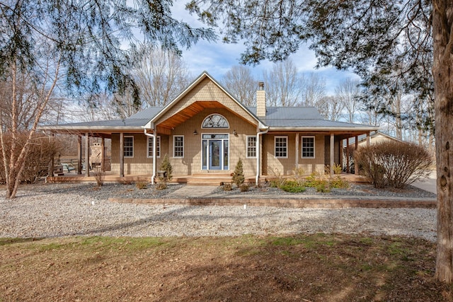 view of front of home with covered porch, metal roof, and a chimney