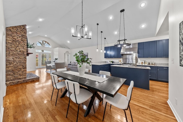 dining area with a chandelier, high vaulted ceiling, arched walkways, baseboards, and light wood-style floors