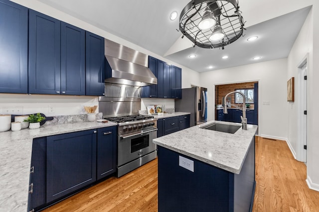 kitchen featuring blue cabinets, wall chimney exhaust hood, stainless steel appliances, and a sink