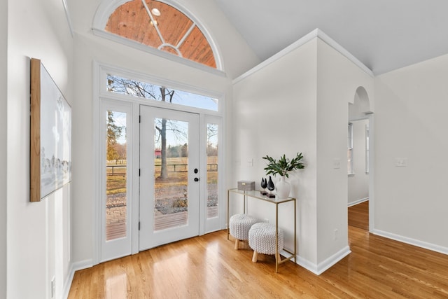 doorway featuring arched walkways, wood finished floors, and baseboards