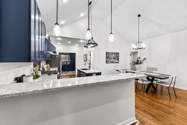 kitchen with a kitchen island, a sink, wood finished floors, a peninsula, and exhaust hood