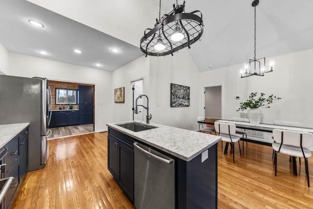 kitchen with stainless steel appliances, light wood-type flooring, a sink, and decorative light fixtures