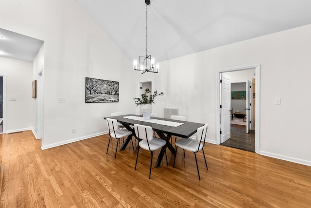 dining space featuring high vaulted ceiling, baseboards, visible vents, and light wood finished floors