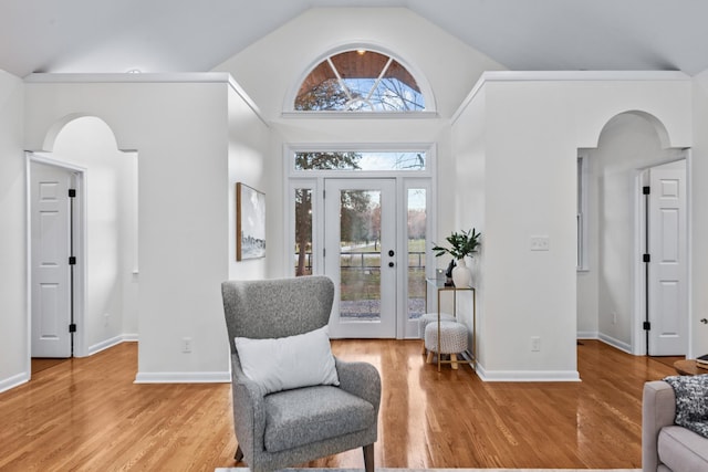 living area with light wood finished floors, baseboards, and arched walkways