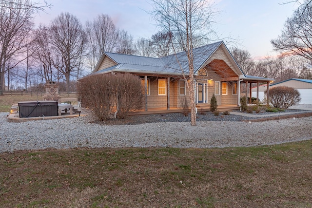 view of home's exterior with covered porch, a hot tub, metal roof, and a yard