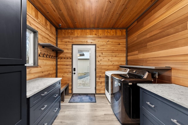 laundry room with wood walls, wood ceiling, light wood-style floors, washer and dryer, and cabinet space