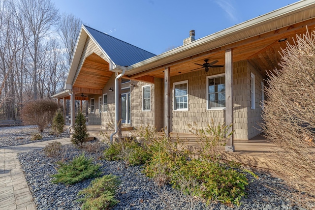 view of side of home with covered porch, a chimney, metal roof, and a ceiling fan