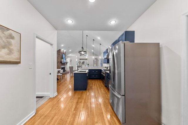 kitchen featuring blue cabinets, stainless steel appliances, a sink, light wood-style floors, and vaulted ceiling