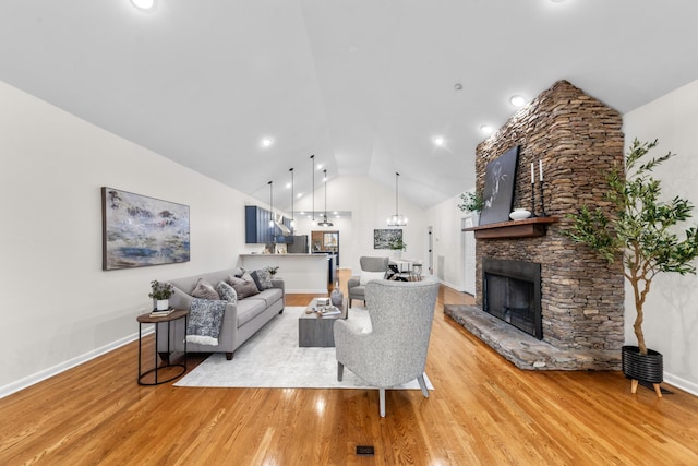 living room featuring lofted ceiling, light wood-type flooring, a fireplace, and baseboards