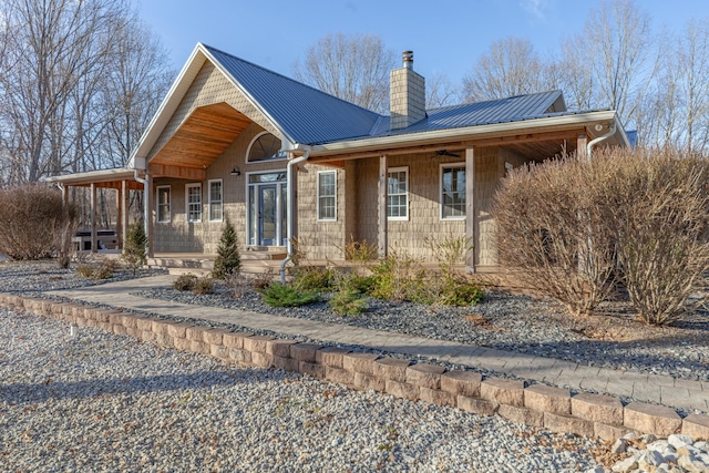 exterior space with metal roof, a porch, and a chimney