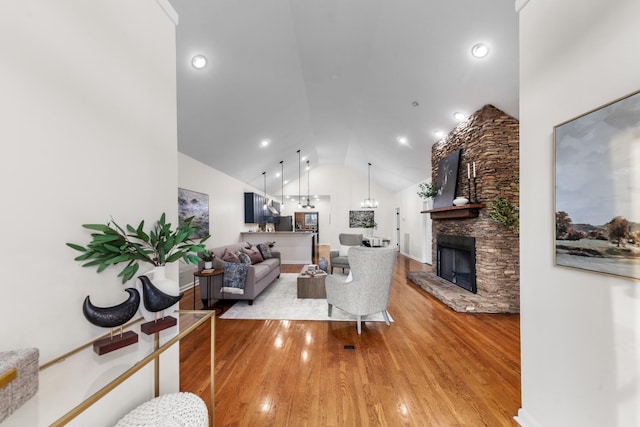 living area with a fireplace, high vaulted ceiling, and wood finished floors