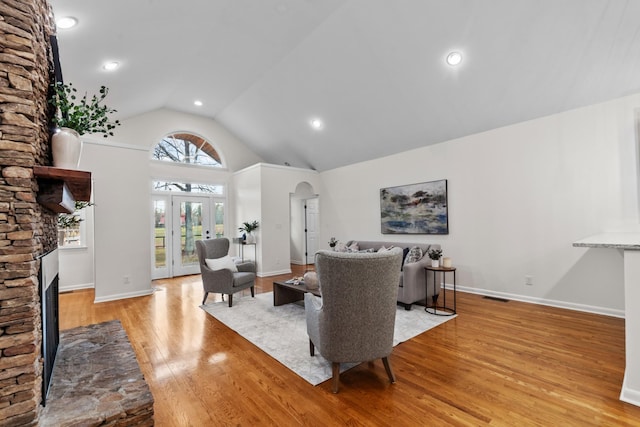 living room featuring visible vents, arched walkways, baseboards, light wood-style floors, and a fireplace