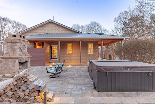 view of patio featuring a hot tub and an outdoor stone fireplace