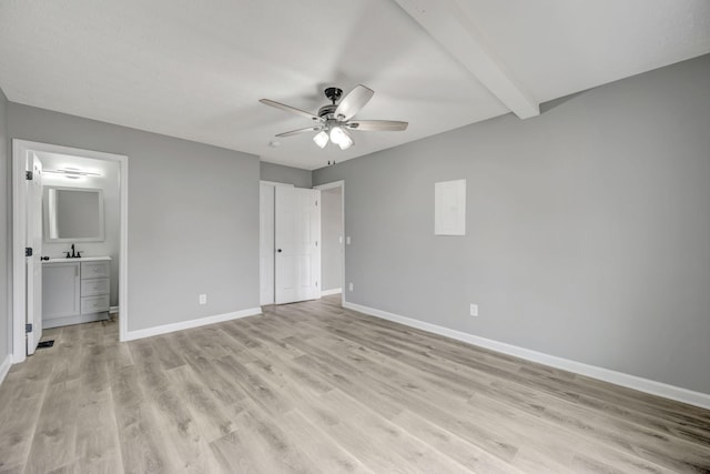 unfurnished bedroom with light wood finished floors, connected bathroom, ceiling fan, beamed ceiling, and baseboards