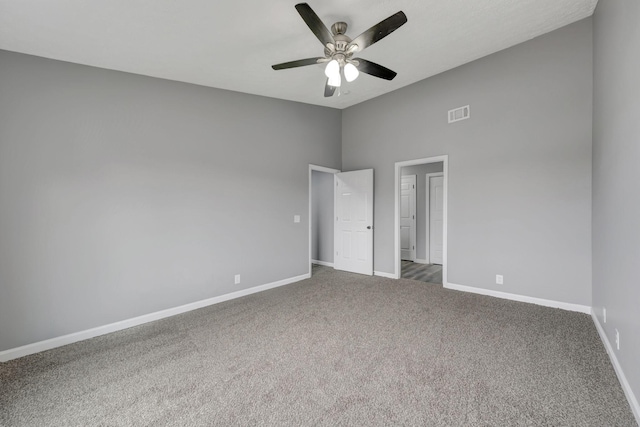 unfurnished bedroom with carpet flooring, a ceiling fan, visible vents, vaulted ceiling, and baseboards