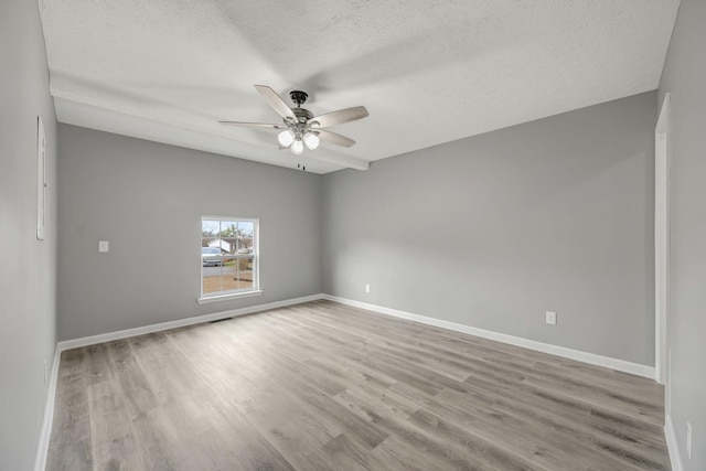 unfurnished room featuring a textured ceiling, ceiling fan, light wood finished floors, and baseboards