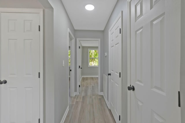 hallway with light wood-type flooring and baseboards