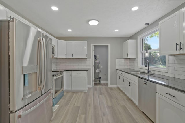 kitchen with stainless steel appliances, dark countertops, white cabinets, and a sink