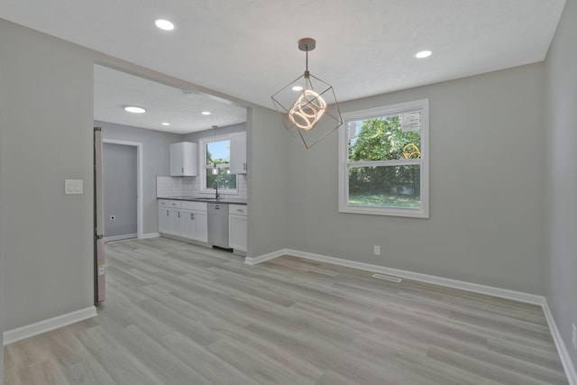 unfurnished dining area featuring recessed lighting, light wood-type flooring, a sink, and baseboards