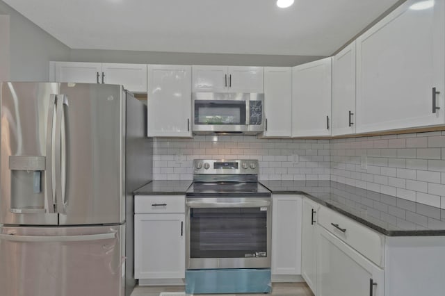 kitchen with stainless steel appliances, dark stone counters, white cabinets, and tasteful backsplash