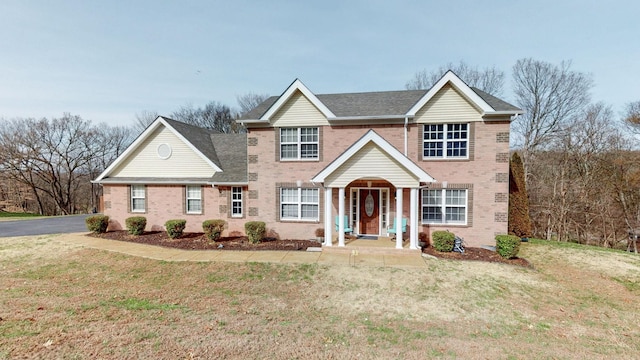 traditional-style home featuring a front lawn and brick siding