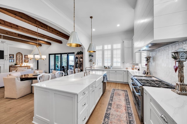 kitchen featuring high end stove, premium range hood, a spacious island, open floor plan, and hanging light fixtures