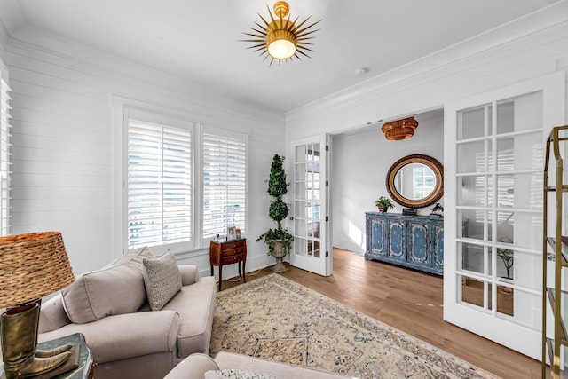 living room featuring light wood-type flooring, french doors, and crown molding