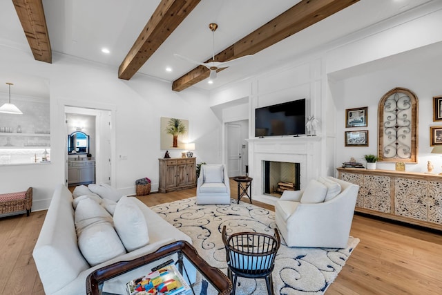 living area featuring light wood-style floors, recessed lighting, beam ceiling, and a fireplace