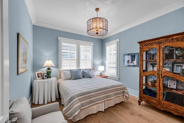 bedroom featuring a notable chandelier, light wood-type flooring, baseboards, and crown molding