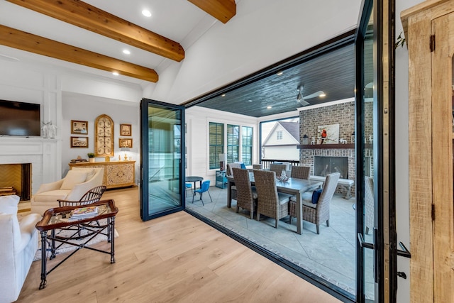 dining area with light wood-style floors, recessed lighting, a fireplace, and beamed ceiling