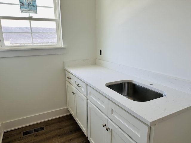 interior space with light stone counters, visible vents, dark wood-type flooring, white cabinets, and baseboards