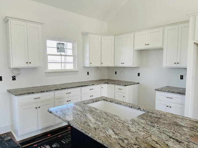 kitchen with stone counters, lofted ceiling, and white cabinets