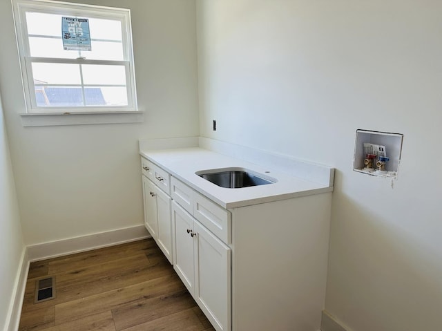 clothes washing area featuring dark wood-style floors, washer hookup, visible vents, cabinet space, and baseboards