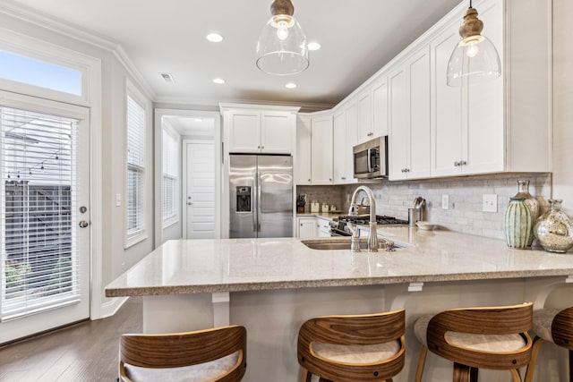 kitchen featuring stainless steel appliances, white cabinetry, backsplash, light stone countertops, and crown molding